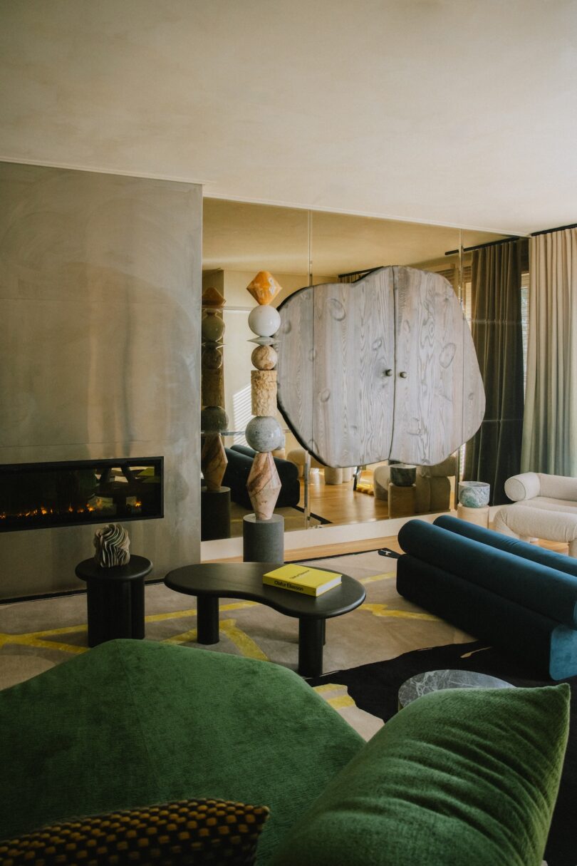 A living room with a fireplace, abstract furniture, and a mirrored wall