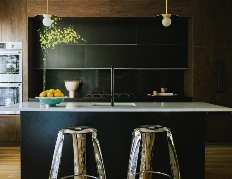 A modern kitchen with a sleek black backsplash, white countertop