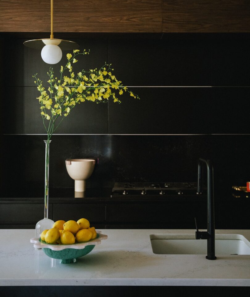 A modern kitchen with a sleek black backsplash, white countertop