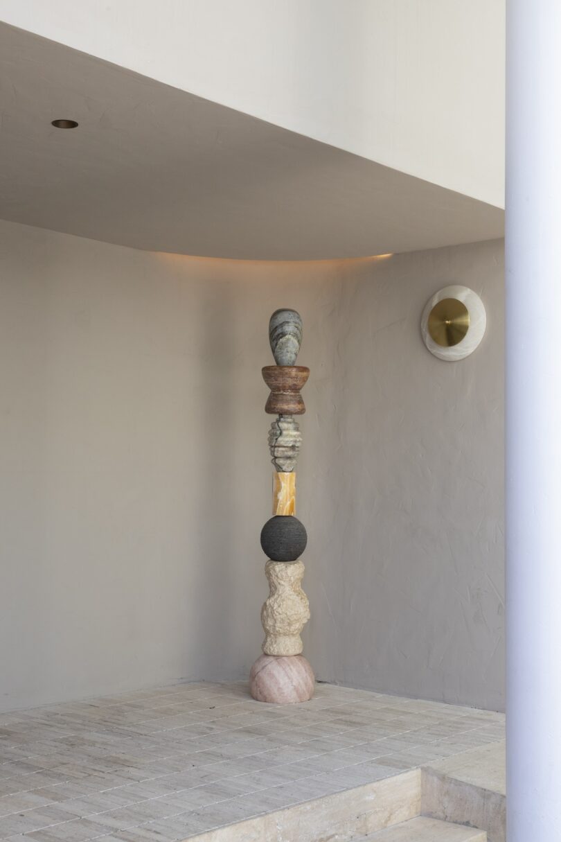 A tall, intricate totem from Sten Studio's "Cosmic Relics" collection, displayed in a minimalistic interior setting