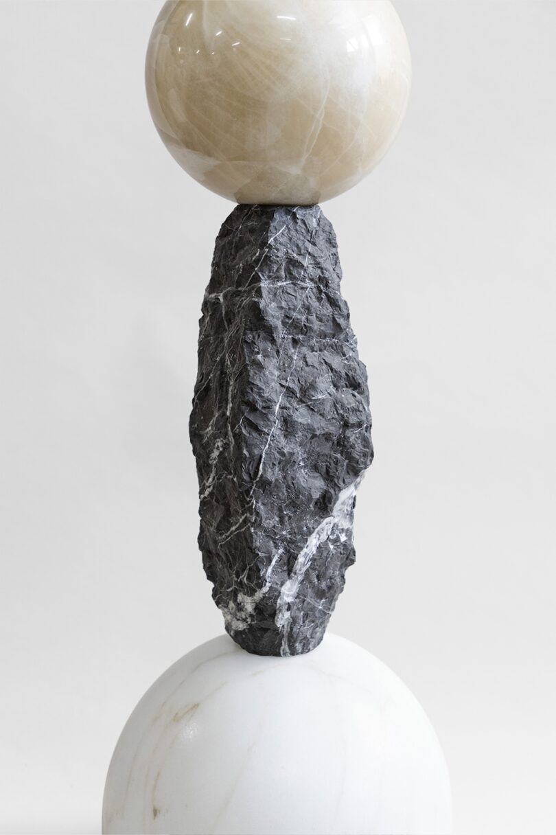 Close-up of a totem from Sten Studio's "Cosmic Relics" collection, showing a rough black stone element topped by a smooth, white spherical stone