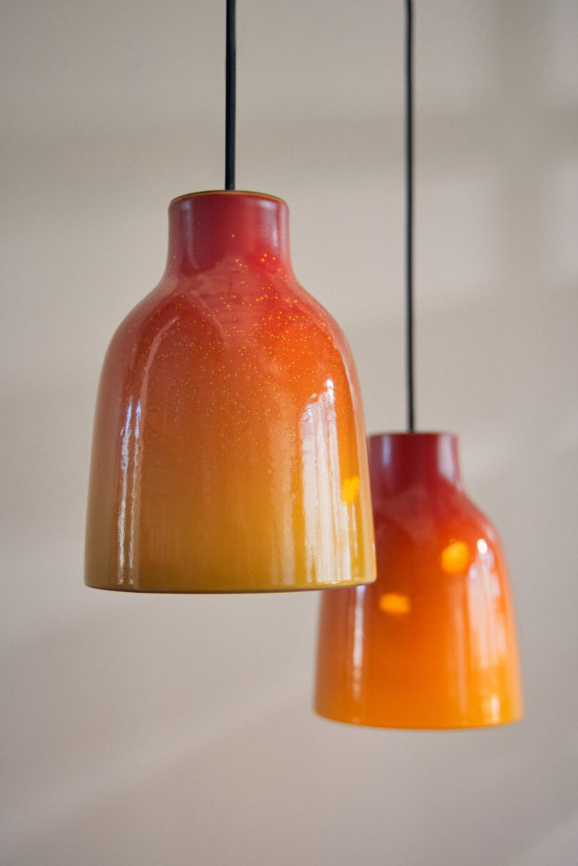 Two glass pendant lights hang from the ceiling, featuring a gradient design that transitions from deep red at the top to yellow at the base.