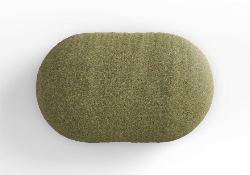 An overhead view of a green, oval-shaped object with a textured surface, resembling a cushion or pouf, set against a plain white background