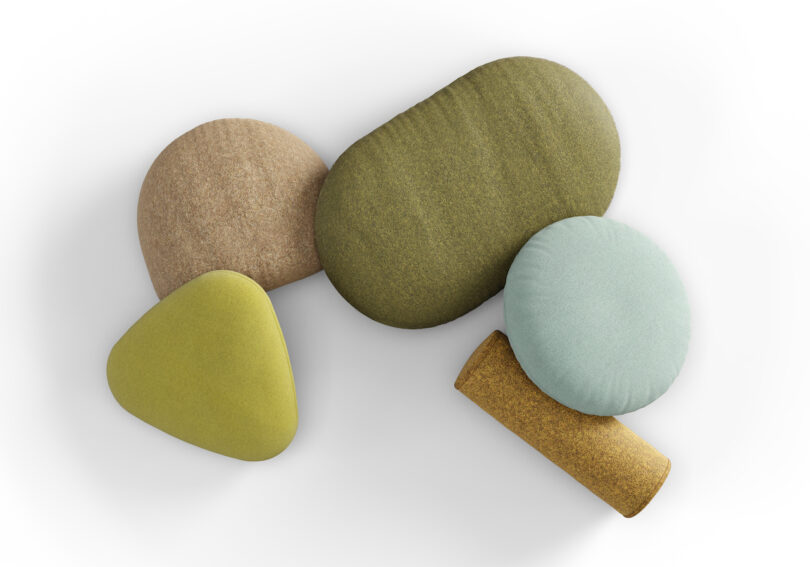 A top view of five variously shaped cushions in shades of green, beige, and yellow, arranged on a white surface