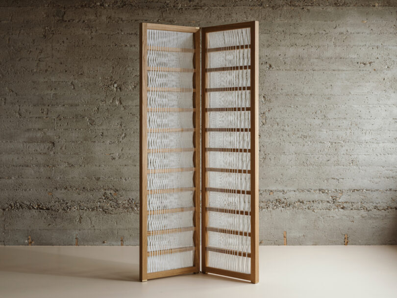 a paper and wood room divider in a room with concrete walls 