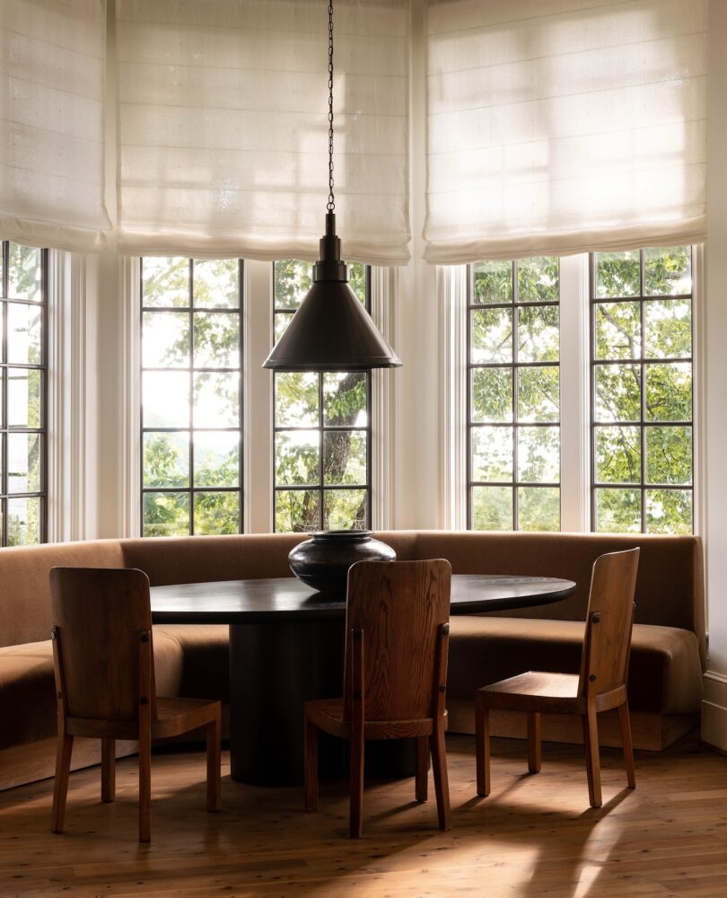 A cozy breakfast nook with a round table, built-in seating, and large windows