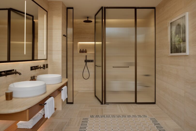A modern bathroom with twin white vessel sinks on a stone countertop