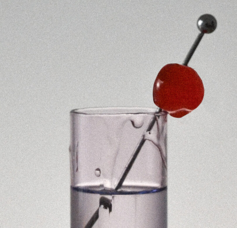 A clear, tall glass with a light beverage and a stirring stick. A red cherry is skewered at the top of the stick