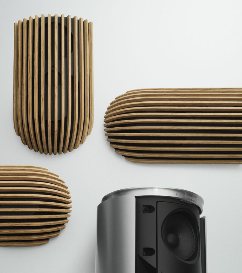 Wall-mounted wooden acoustic panels and a metallic Beolab 8 speaker with an exposed woofer are depicted against a plain white background.