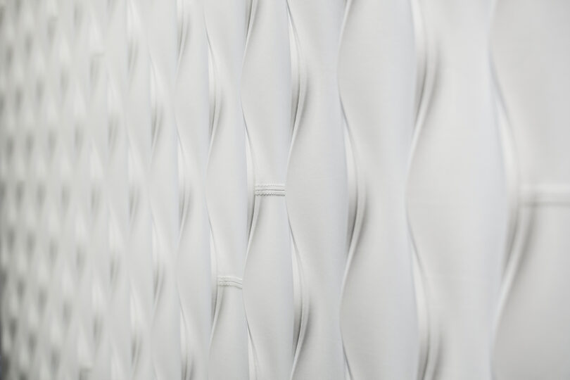 A close-up of a textured, white padded wall, Design 406 by Erwin Hauer, with a diamond pattern.