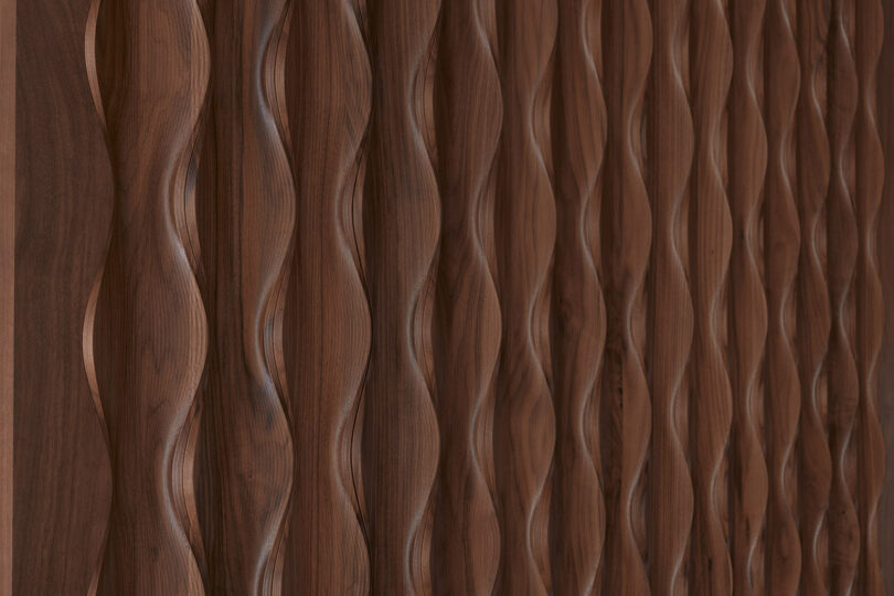 Close-up of a textured wooden panel, Design 406 by Erwin Hauer, featuring vertical, wavy grooves and a polished brown surface.