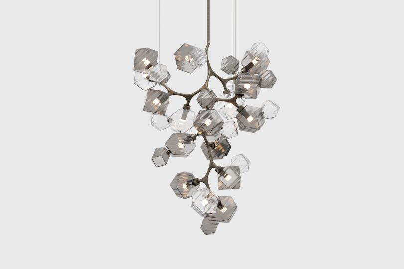 A cluster of geometric pendant lights with a metallic frame, featuring multiple clear, faceted glass shades, hung together in a sculptural design