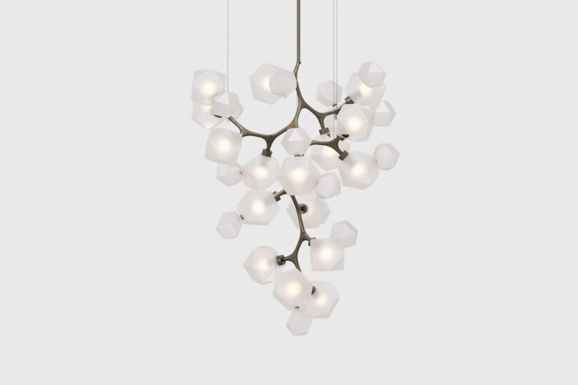 A modern chandelier with multiple geometric glass pendants, some tinted amber and others clear, hanging from thin wires