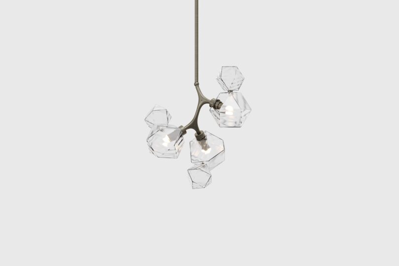 A modern pendant light fixture with five geometric, transparent glass shades on a bronze-colored metal frame