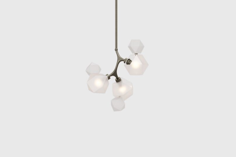 A modern ceiling light fixture with five geometric white glass shades and a metal structure.