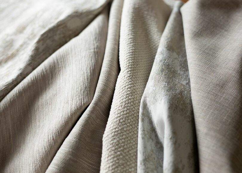 Close-up of various beige fabric swatches arranged side by side, showcasing different textures and patterns.