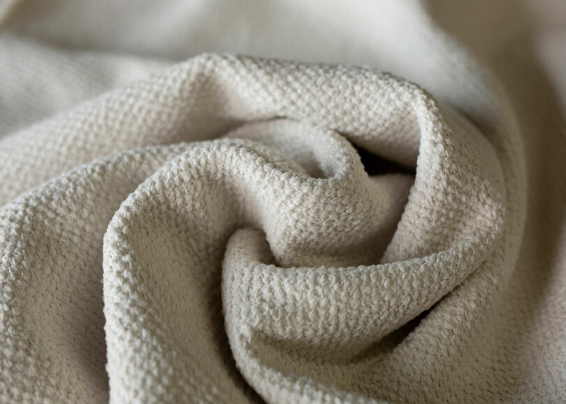 Close-up of a textured beige fabric with soft folds and gentle draping.