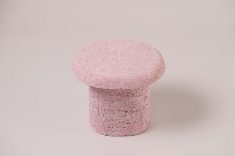 A pink, round-topped table from the Pastille Collection by Emeline Ong with a cylindrical base on a plain white background.