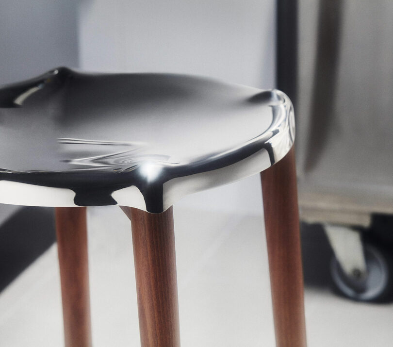 The Poele Stool by Philip Starck and Alessi is shown, focusing on the reflective and smooth surface of the seat.