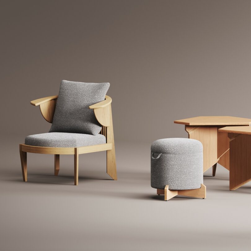 A modern wooden armchair with gray cushions, influenced by the design principles of Frank Lloyd Wright, is paired with a matching gray cushioned stool and a geometric wooden side table, all set against a neutral background.