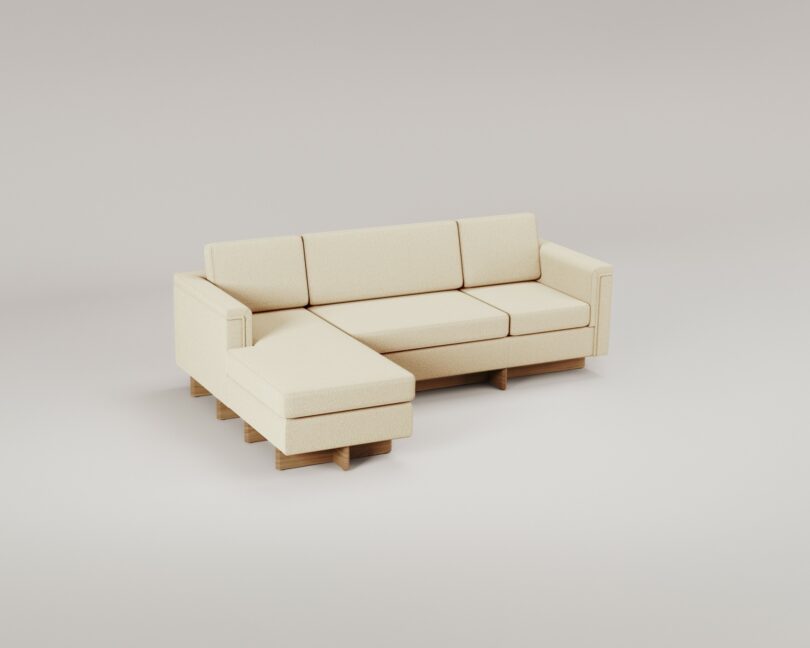 A beige sectional sofa with an L-shaped design, featuring wooden legs and wide armrests, reminiscent of Frank Lloyd Wright's architectural style, is set against a plain, light-colored background.