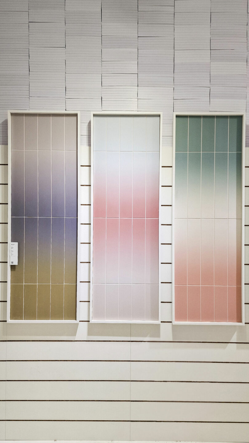 Three framed displays of gradient-colored tiles (brown to blue, pink to white, and green to pink) are mounted on a wall.