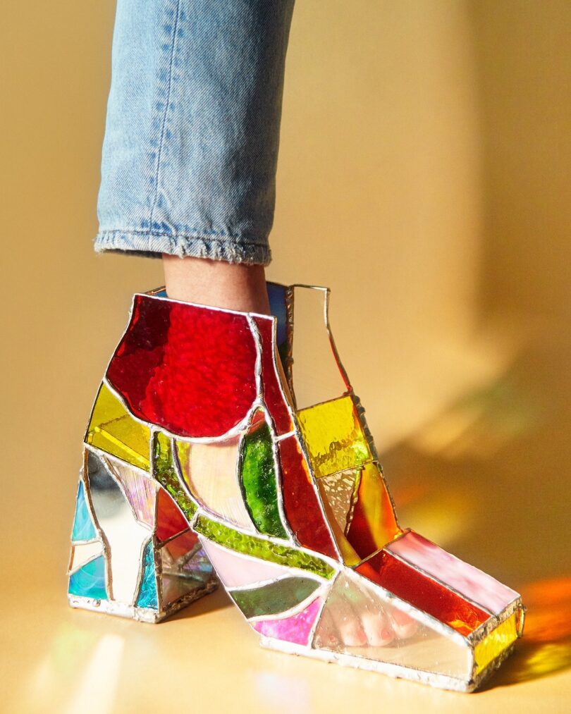 A person's foot, partially visible, is wearing a boot made of colorful stained glass pieces