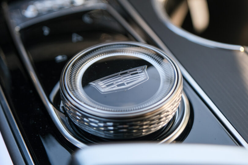 Close-up of a Cadillac gear shift knob in a car's center console, featuring the Cadillac logo.