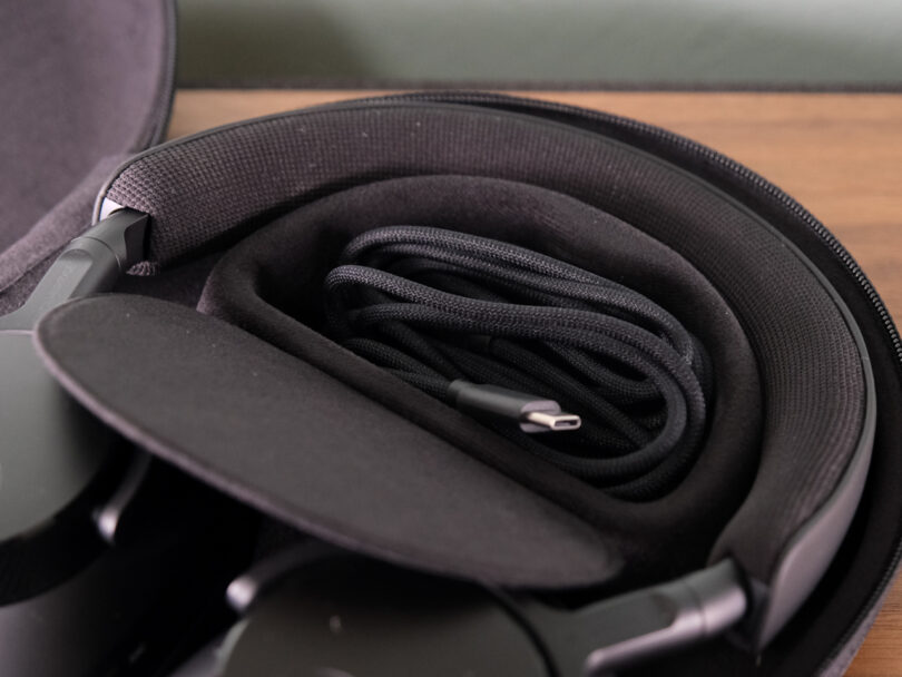 A close-up of a black case containing neatly coiled black cables and other accessories, perfect for your Melomania P100.