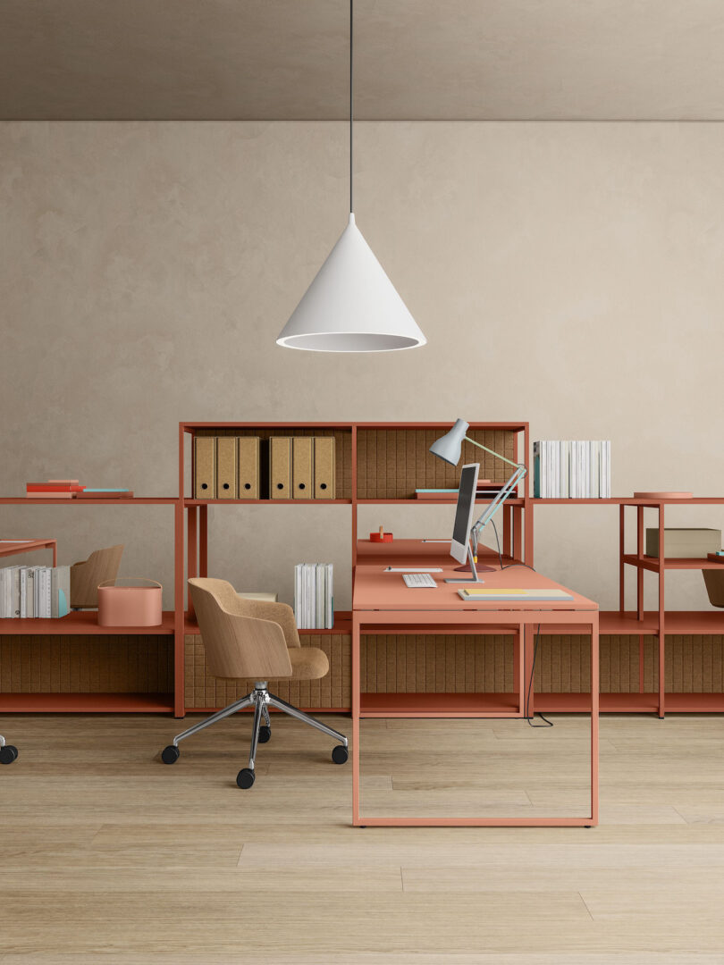 A minimalist office space with a wooden desk, a modern chair on wheels, shelves with books and files, a desktop computer, and a cone-shaped hanging light above