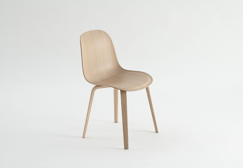 A simple, light wood chair with a curved backrest and four legs on a plain white background