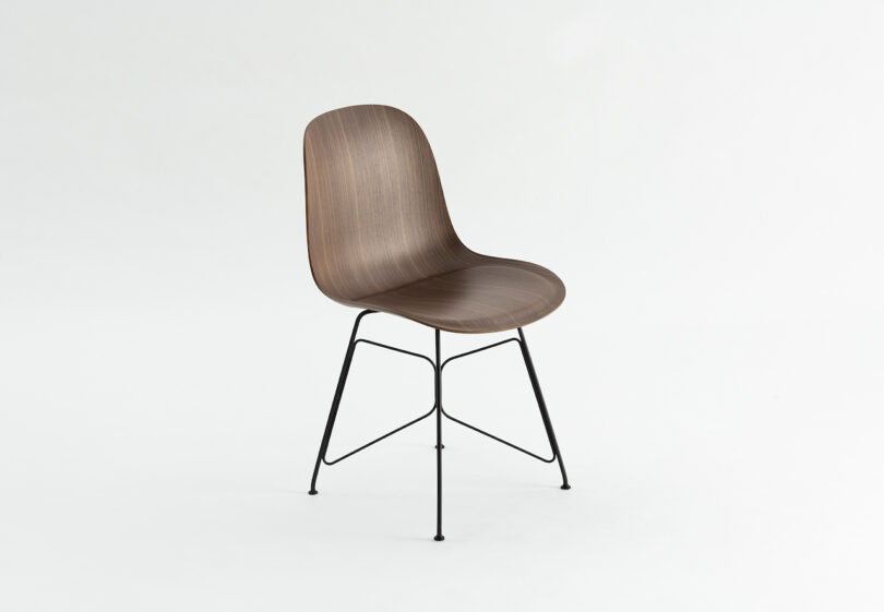 A modern chair with a smooth, curved wooden seat and backrest, mounted on a black metal frame with four legs