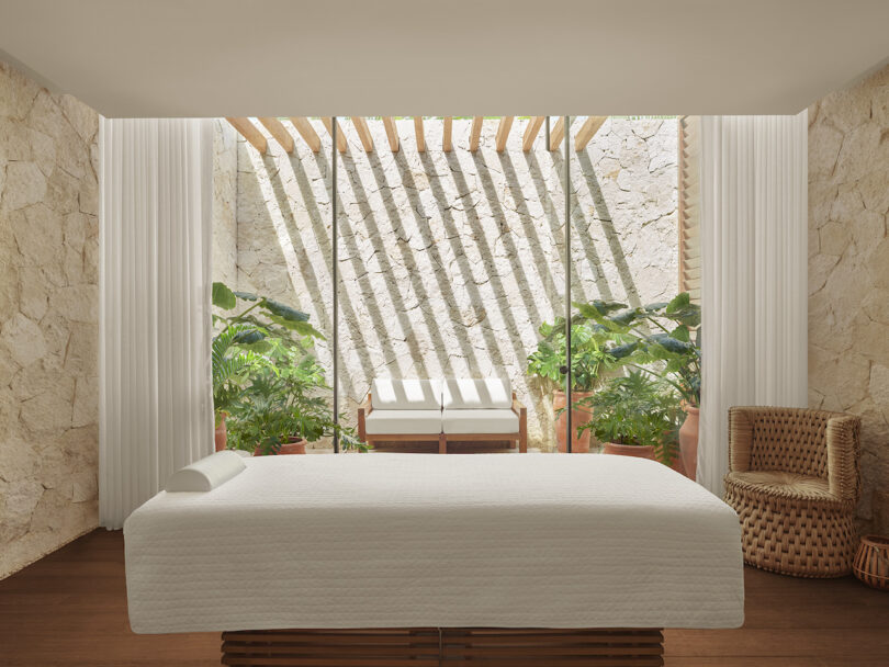 A serene spa treatment room at The Riviera Maya EDITION, with stone walls, natural light, and lush plants