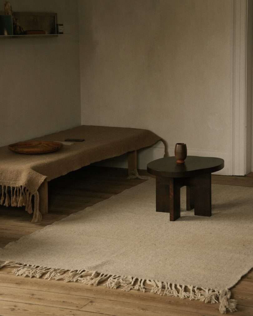 A minimalist room adorned with a Beni rug, a wooden table, and simple furnishings