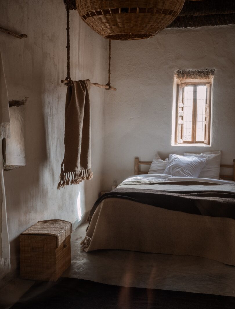 A serene bedroom featuring a woven Beni rug, earthy tones, and natural light filtering through a small window