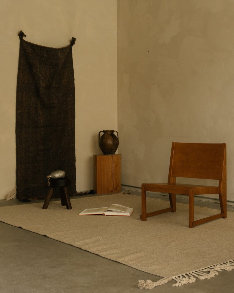 A simple, serene corner with a light Beni rug, a wooden chair, and a rustic pottery accent