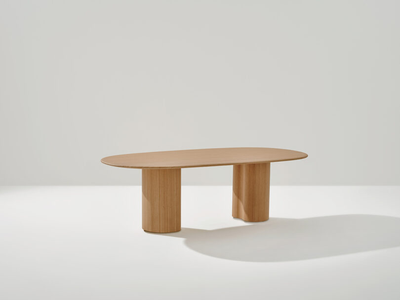 A Ghia Table with a flat top and two cylindrical legs, set against a plain white background.