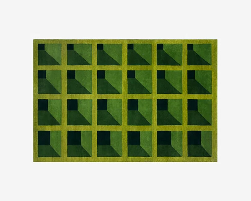 An image of a rectangular rug with a grid of squares in shades of green, featuring a 3D effect that makes each square look like a cube with a shadow—perfect for giving your space some bratty flair.