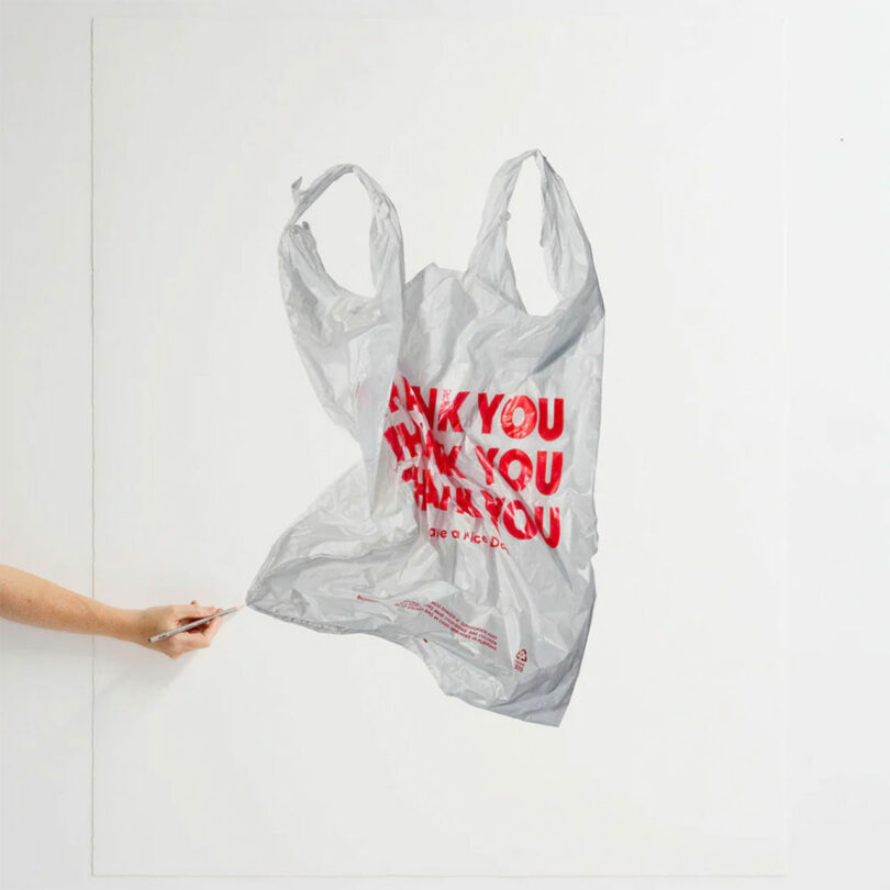 An artist's hand expertly holding a pencil while drawing a realistic plastic bag with "Thank You" written on it multiple times in red letters.