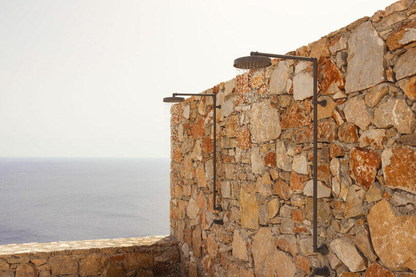 Outdoor stone wall with two showerheads overlooking the ocean.