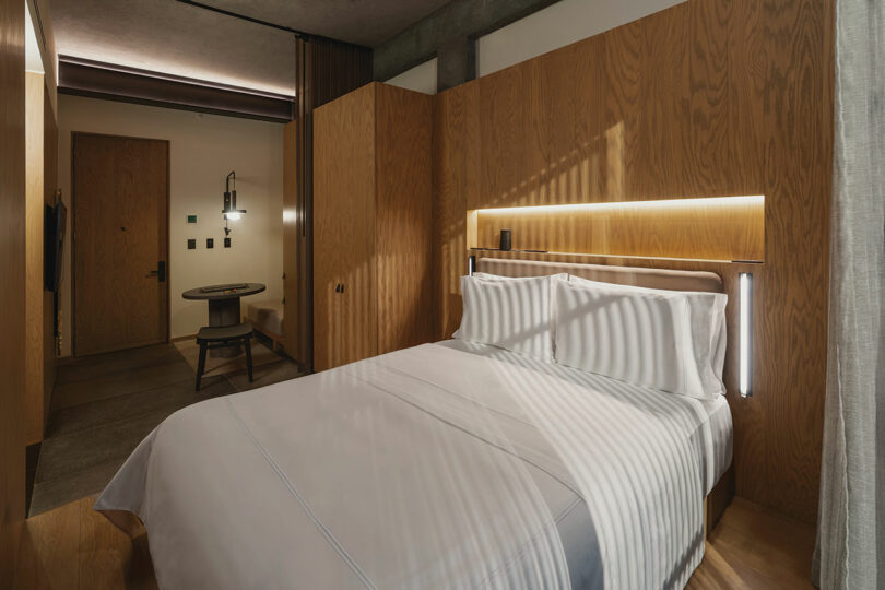 A modern Hotel Volga room features a neatly made bed, wooden furnishings, a small table with chairs, and ambient lighting.