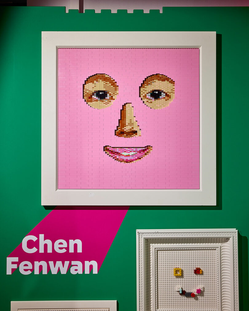 Framed pink face artwork made from small colorful tiles on a green wall with the name "Chen Fenwan" displayed below it.