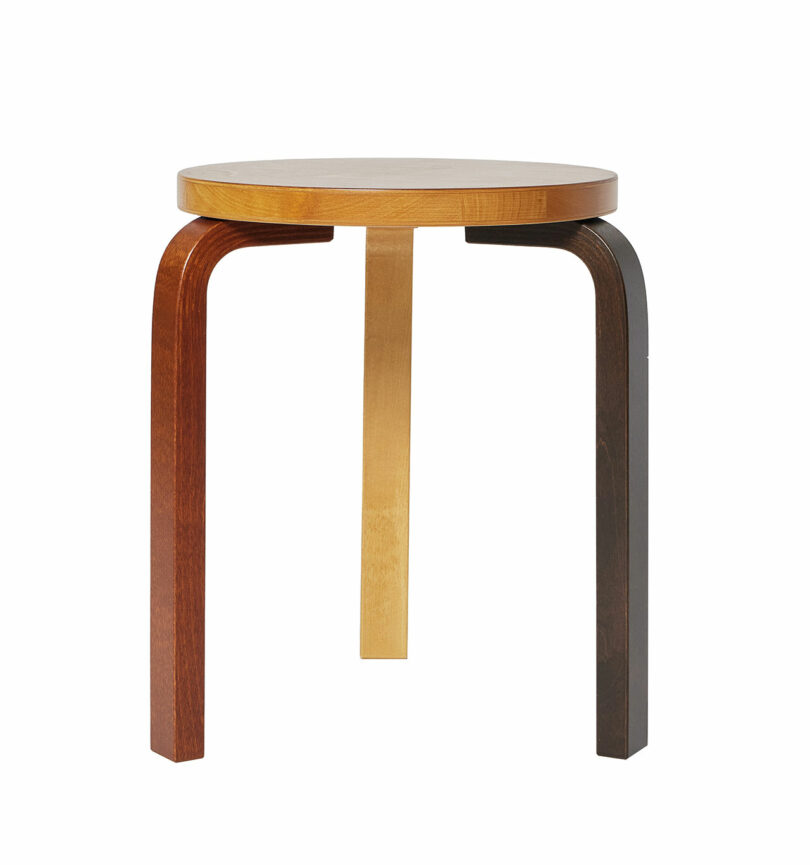 Stool 60 by Alvar Aalto, each leg painted a different color: brown, yellow, and black.