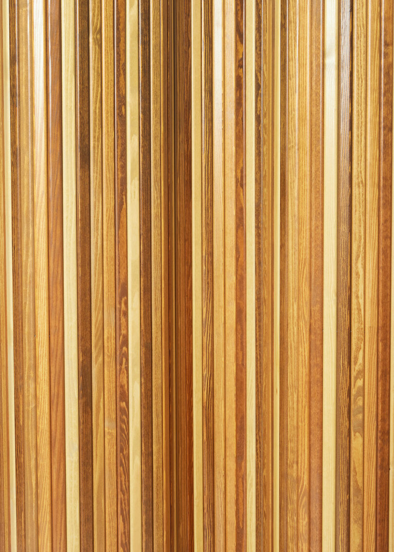 Close-up view of Screen 100 by Alvar Aalto, multiple vertical wooden planks of various shades arranged side by side.