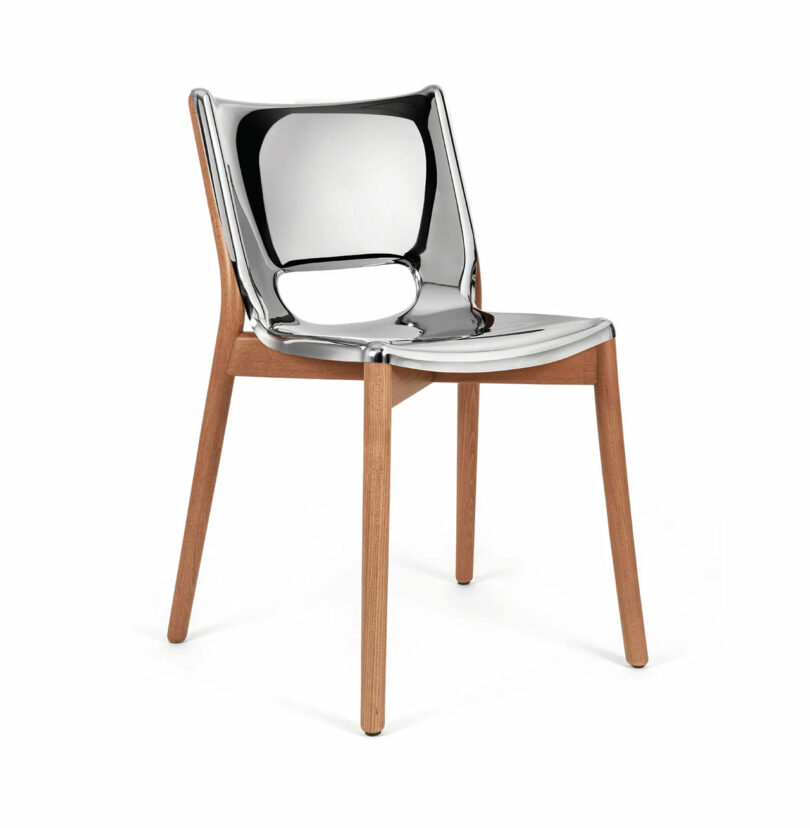 Part of the Poele Collection by Alessi, this modern chair features a reflective, metallic seat and backrest, elegantly supported by wooden legs.