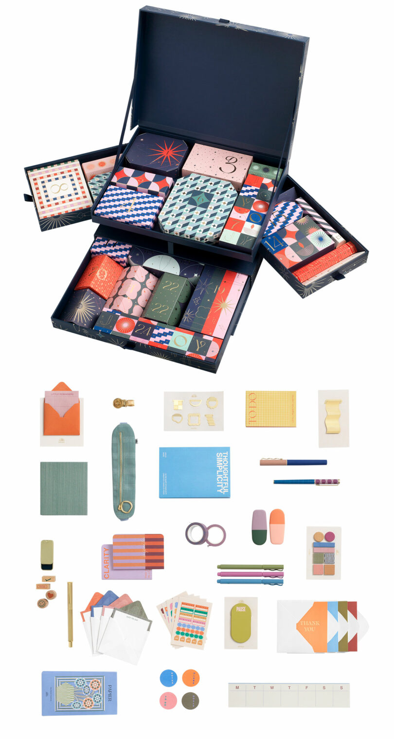 Open box with various colorful stationery items neatly organized inside and displayed separately below, including notebooks, paper clips, stickers, and writing tools.