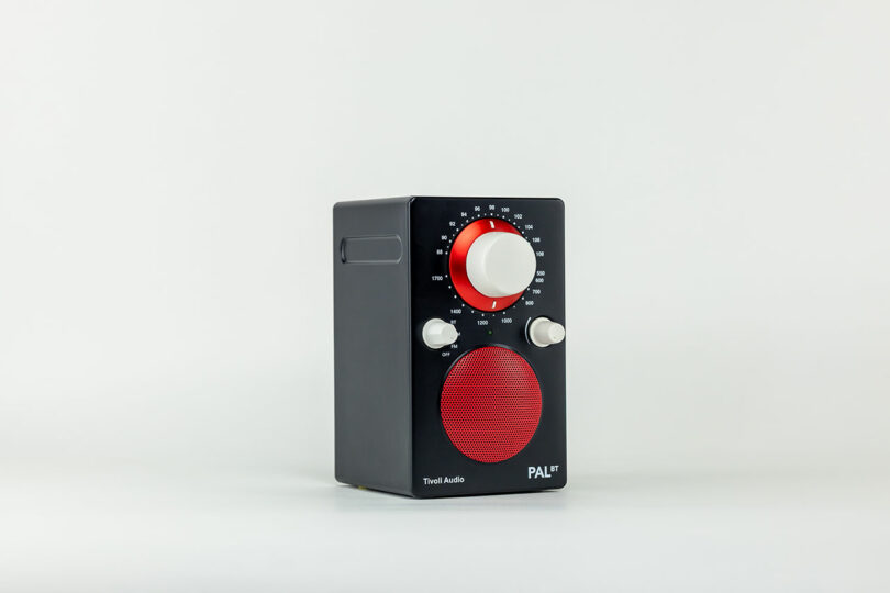 A black and red Tivoli Audio PAL BT radio with tuning and volume knobs, featuring a compact, rectangular design set against a plain white background. The sleek design underscores Tivoli Audio's commitment to blending functionality with style.