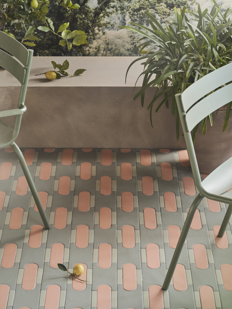 A patio with Tivoli Tech tiles, two green chairs, a potted plant, and lemons, including one lemon on the floor.