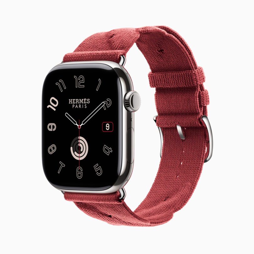 Apple Watch with Hermès Paris branding, featuring a square face displaying an analog clock and a date, attached to a red fabric strap.