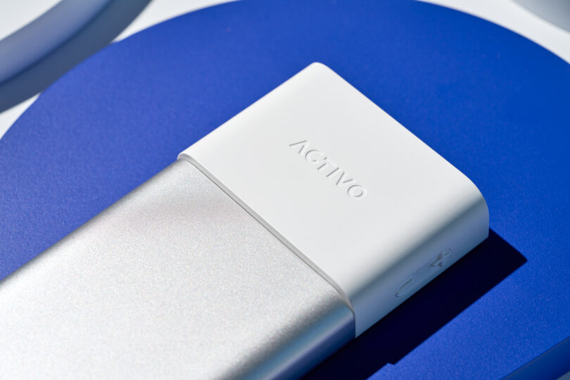 Close-up of a silver and white ACTIVO branded Astell&Kern P1 electronic device on a blue surface.